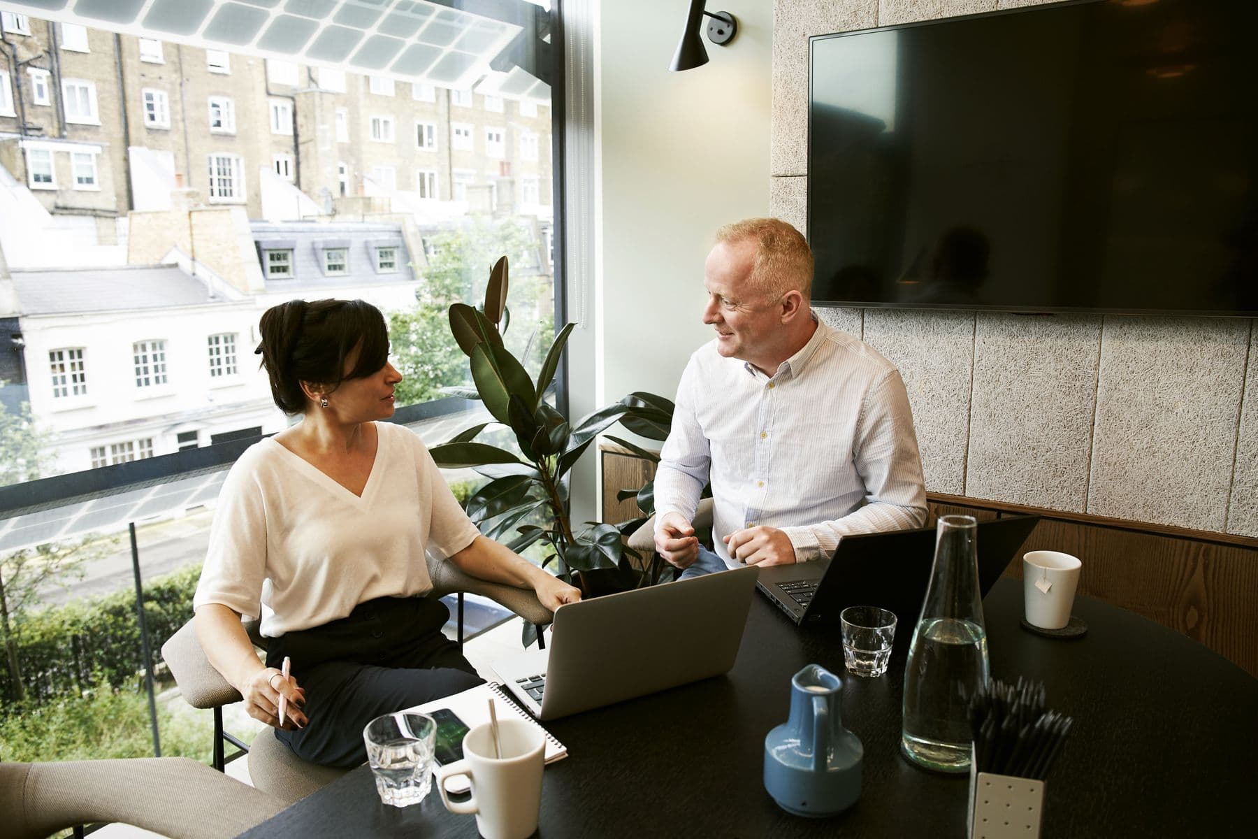 Two colleagues talking through enquiries at a table in a London office